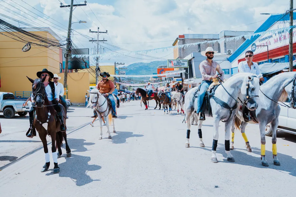Caballos y jinetes avanzan por una calle durante una actividad de feria