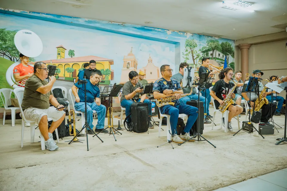 Músicos ensayan juntos en una sala con instrumentos de viento y percusión