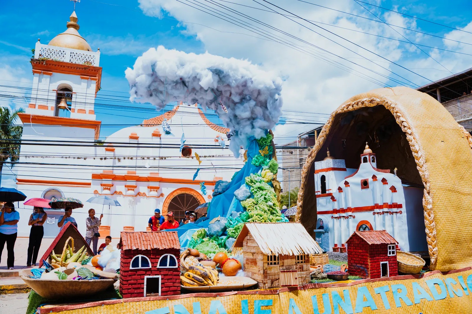Carroza decorada con formas de casas y una iglesia en una calle durante la feria de Yoro